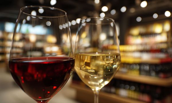 Ett glass rött och ett glas vitt vin framför Systembolaget butik